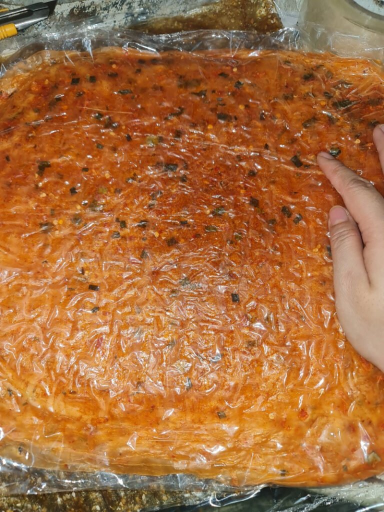 Bánh tráng dẻo tôm có màu đỏ của ớt, bề mặt trên của bánh có nhiều con ruốc